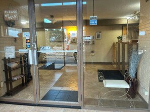 A hotel entrance with a glass door, a 'Please No Pets' sign, a 'Pull' sign, and a 'Come In' sign.