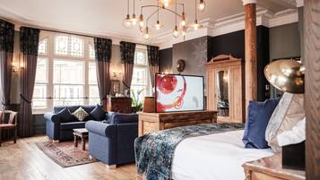 A bedroom with a large bed, a sofa, a wooden cabinet, and a television.