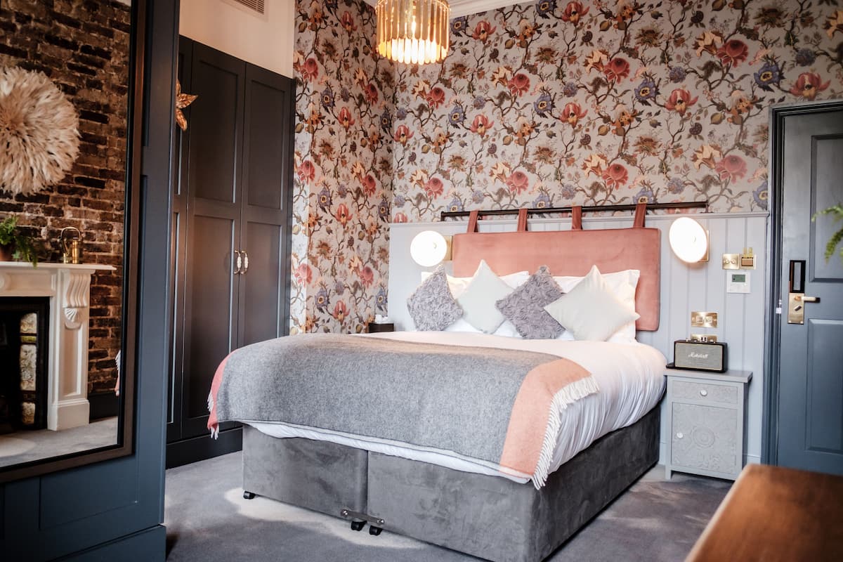 A bedroom with a large bed, a nightstand, a dresser, and a mirror.