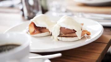 A breakfast plate with eggs benedict and a cup of coffee.