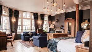 A spacious room with a large bed, two sofas, a wooden desk, and a fireplace. - Half Moon (London)