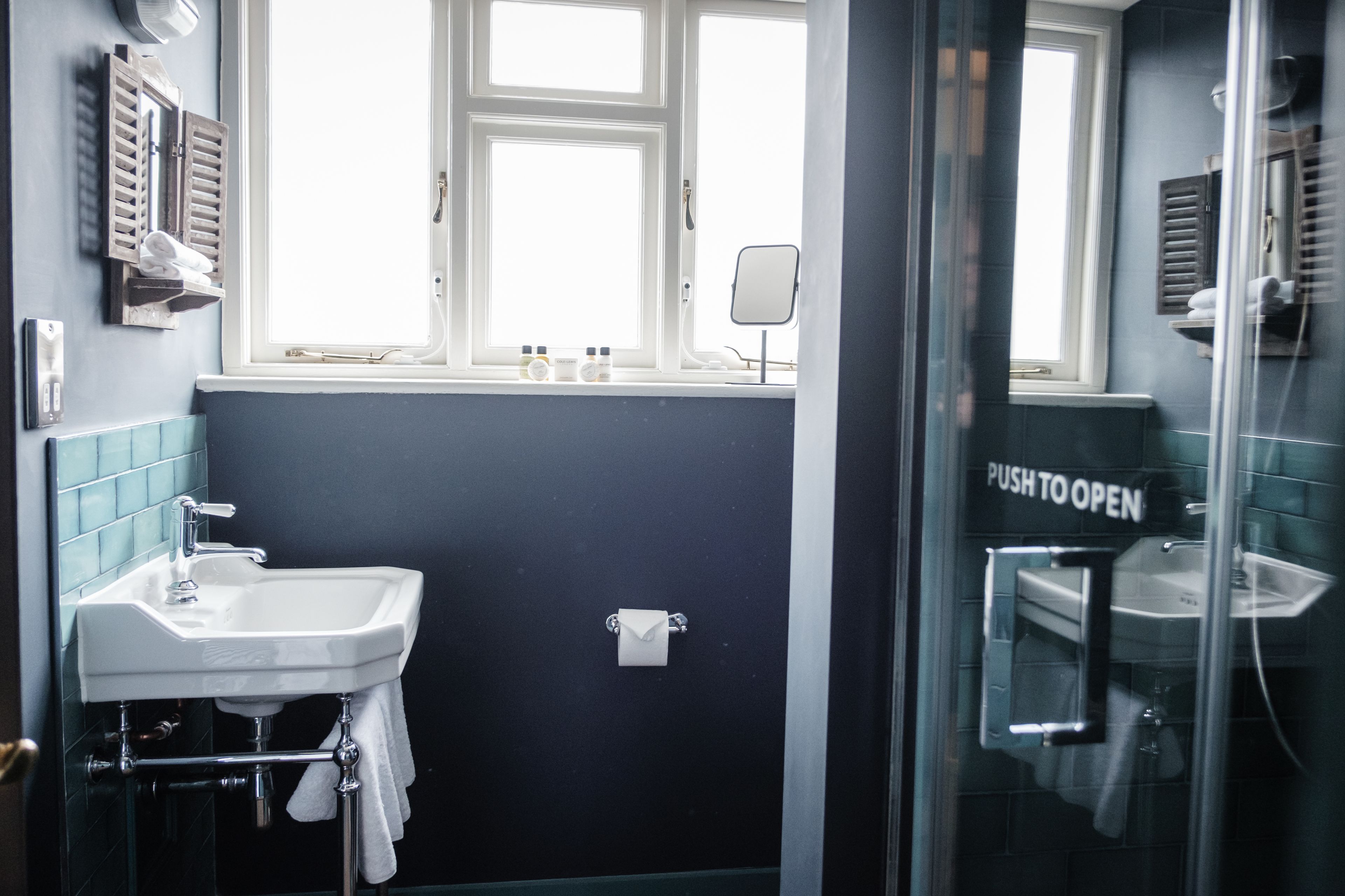 Un baño con lavamanos, espejo y ventana.