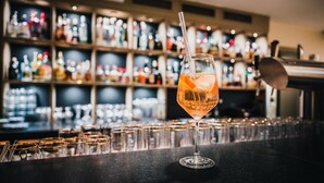 Een barsetting met een cocktailglas op de bar, flessen op de achtergrond en een rij glazen.