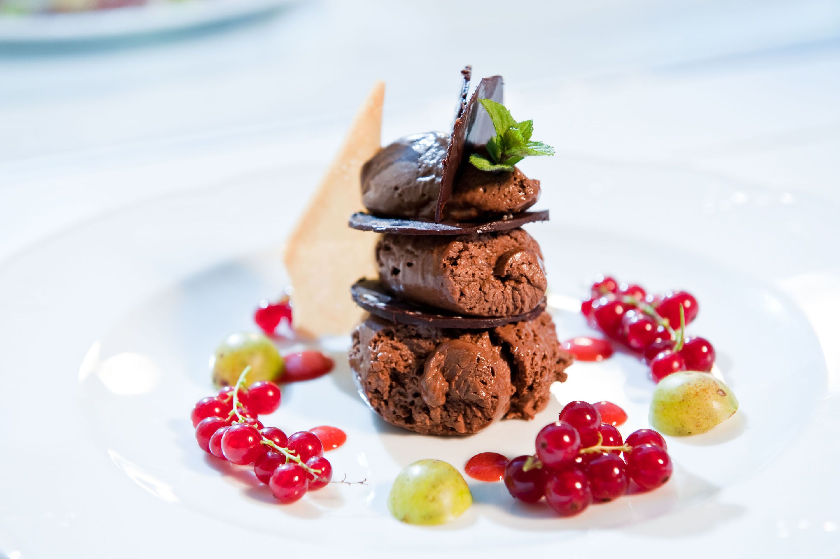 Un postre con helado de chocolate y adornos sobre un plato blanco.