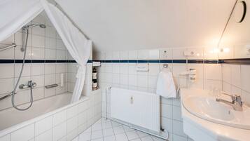 Een badkamer met een bad, douche, wastafel en toilet.