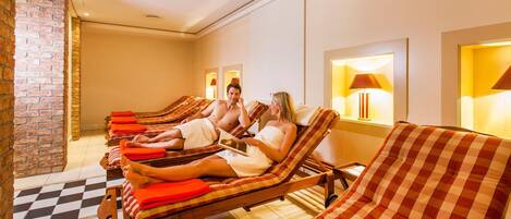Zona de spa con varios sillones de sol, suelo a cuadros y pared de ladrillo.