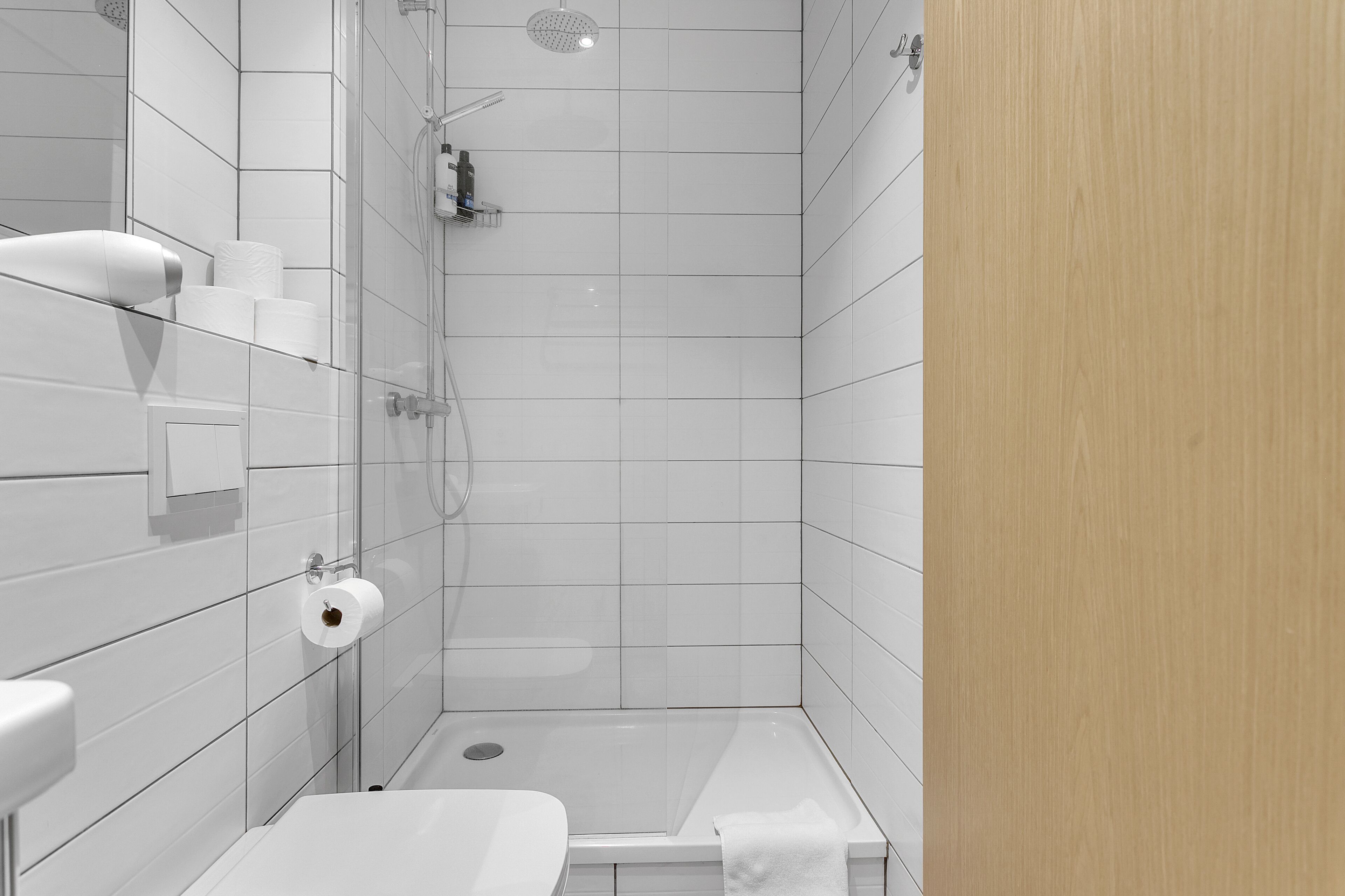 A modern bathroom with a glass shower enclosure, a toilet, and a sink.