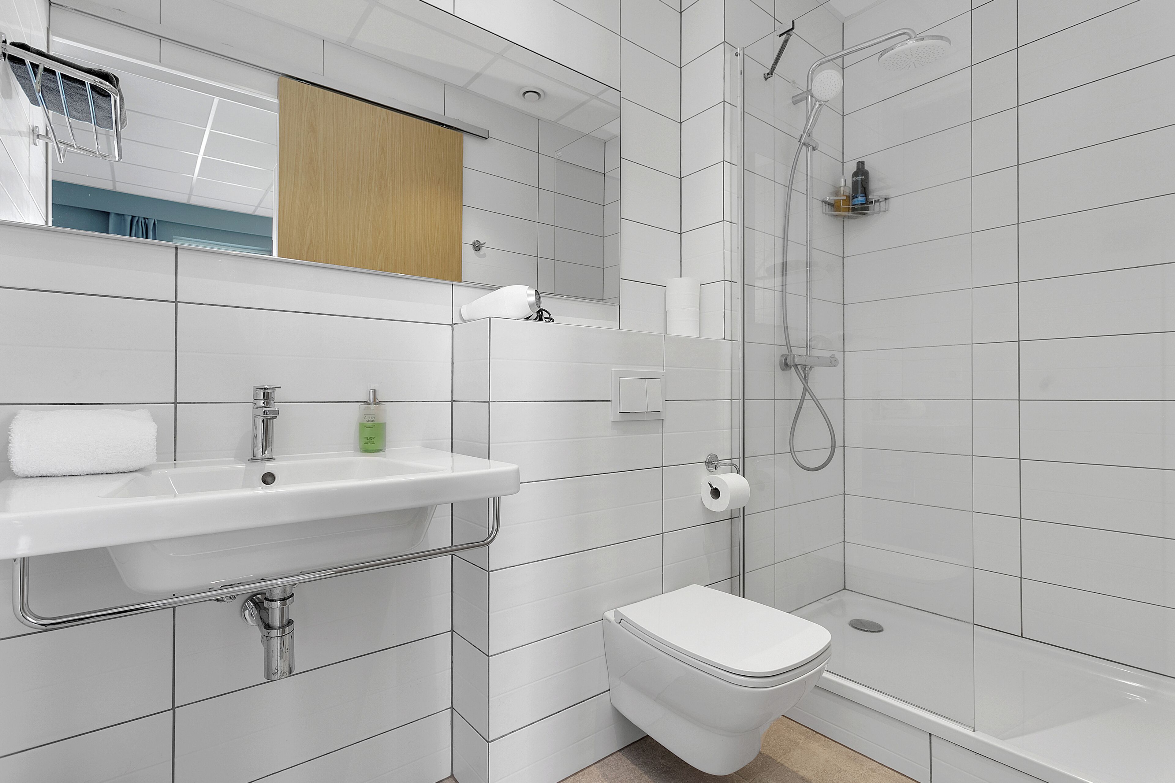 A modern bathroom with a white sink, toilet, and shower.
