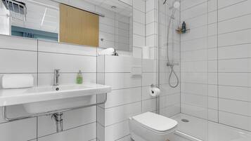 A modern bathroom with a white sink, toilet, and shower.