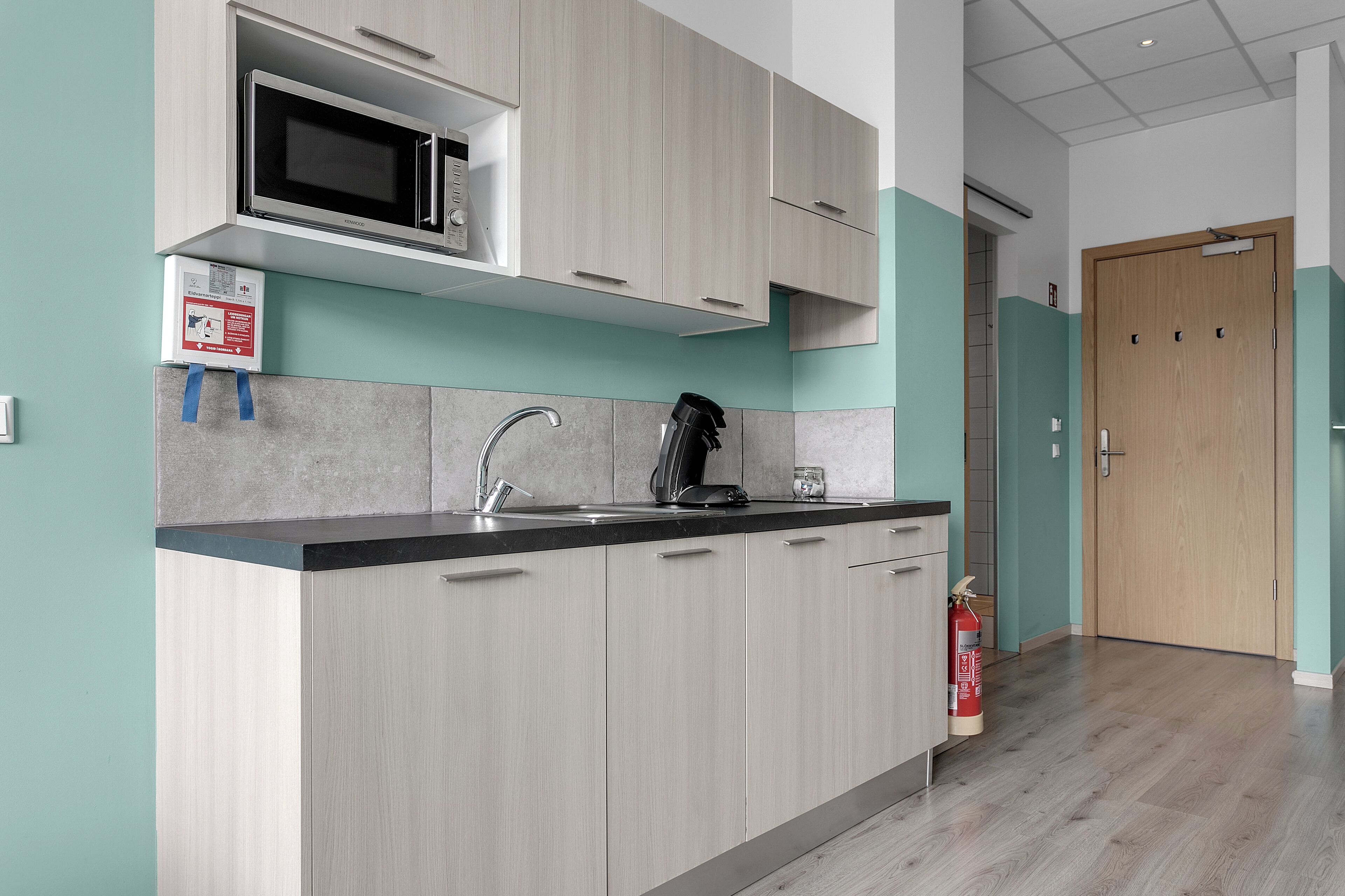 A modern kitchen with a built-in microwave, a coffee machine, and a sink.
