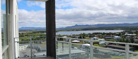 A balcony with a view of a lake, buildings, and mountains.