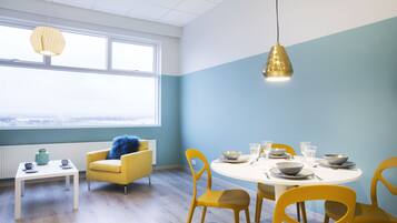 A dining area with a round table set for four, yellow chairs, and a window with a view.