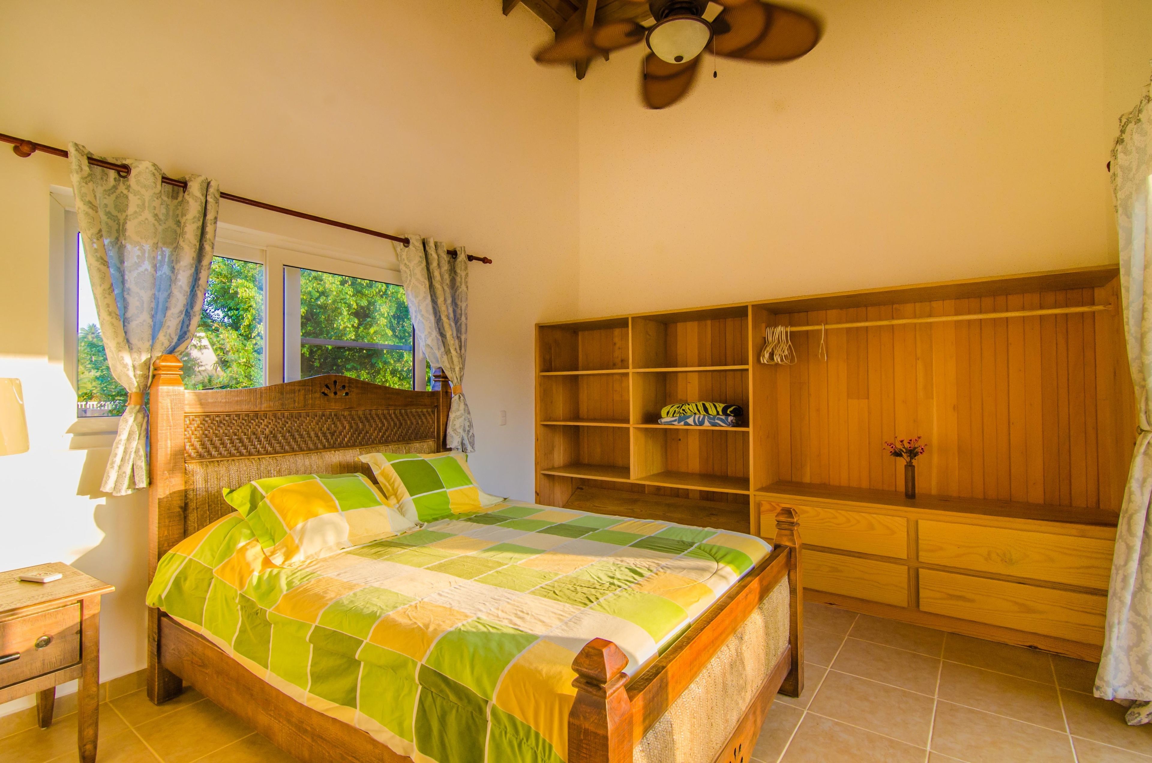 Un dormitorio con una cama de madera, un armario de madera y un ventilador de techo.