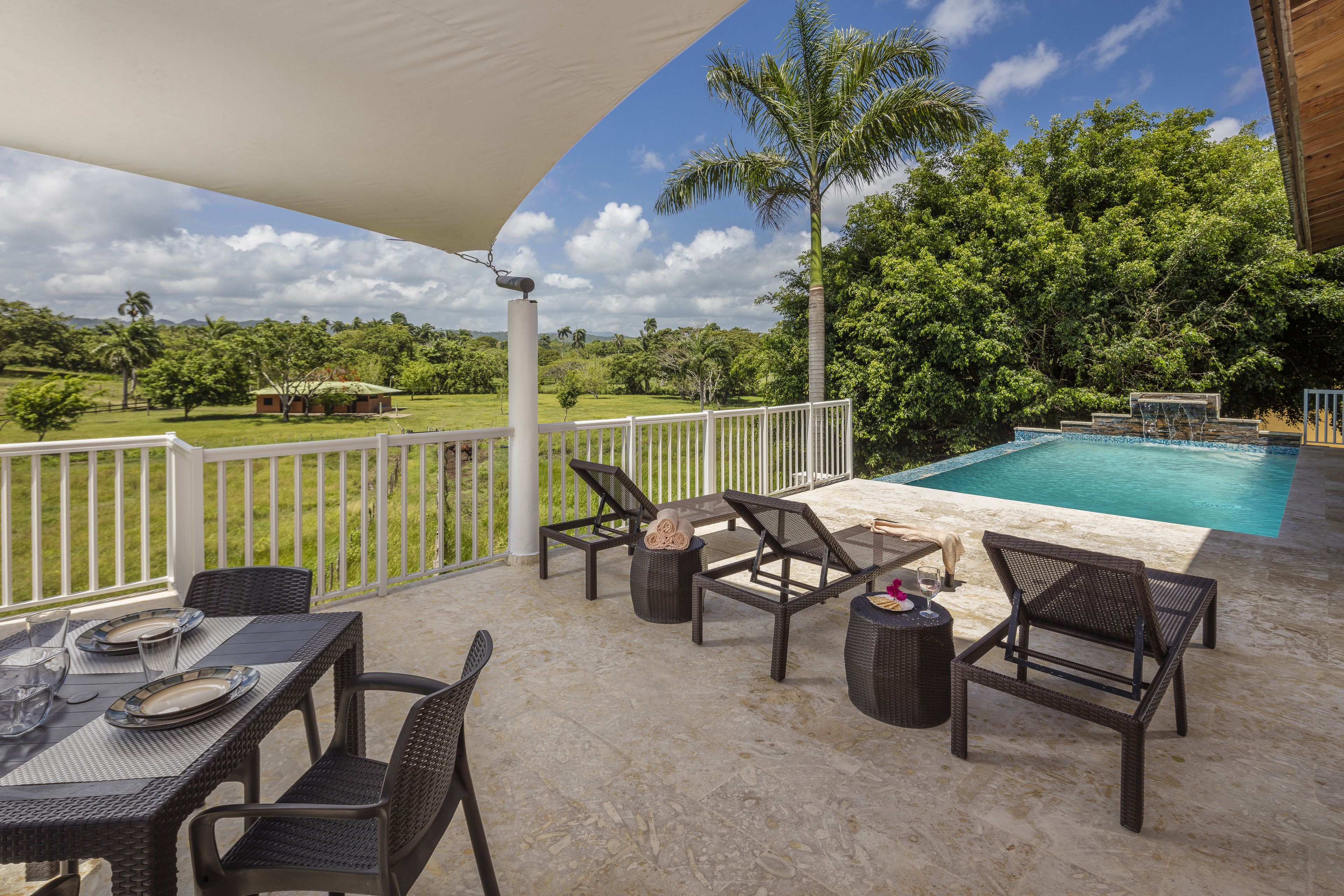 An outdoor patio with a pool, wicker furniture, and a view of the surrounding landscape.