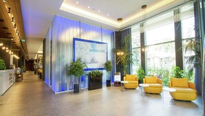 A modern lobby with a reception desk, seating area, and large windows offering views of the outdoors. - Hampton by Hilton Bolu (Bolu)