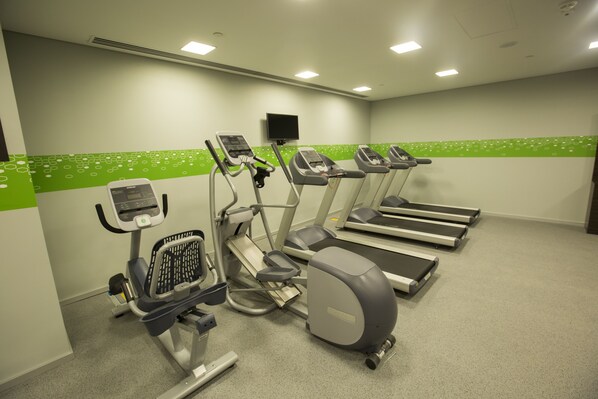 Un gimnasio con cintas de correr, una elíptica y una bicicleta estática.
