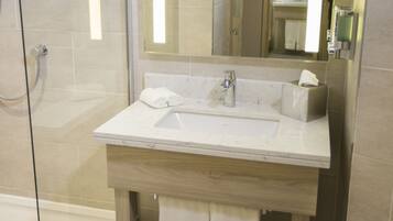 A modern bathroom with a glass-enclosed shower, a white sink, and a large mirror.