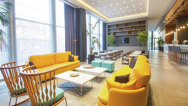 A spacious lobby with a yellow sofa, wooden rocking chairs, and a bar area. - Hampton by Hilton Bolu (Bolu)