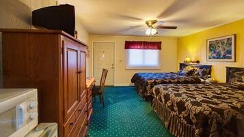 A bedroom with two beds, a ceiling fan, a window with red curtains, and a painting on the wall.