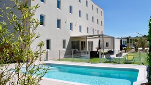 Un edificio moderno con piscina, asientos al aire libre y césped bien cuidado.