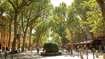 Una calle arbolada con peatones, bancos y edificios.