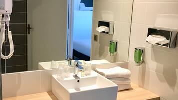 Un bagno moderno con uno specchio grande, due lavabi, un asciugacapelli e un water.