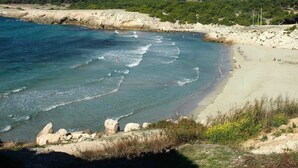 Una playa costera con aguas transparentes, un litoral rocoso y una zona de arena.