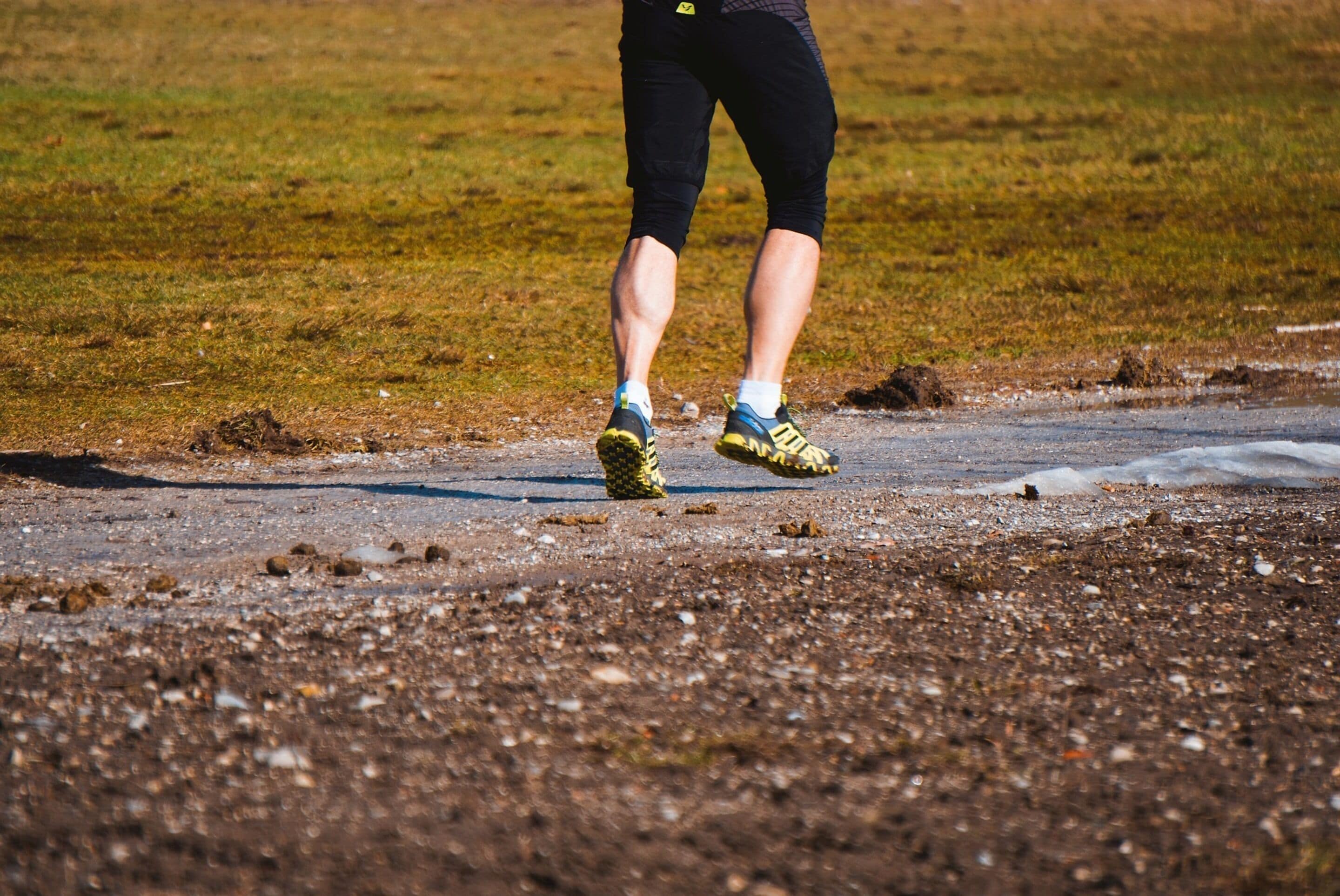 A person walking on a gravel path with grass on either side.
