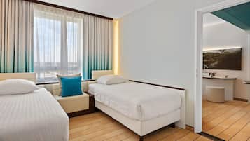 Une chambre d’hôtel avec un lit, une table de chevet, une chaise, une fenêtre avec des rideaux, un tableau au mur et un petit tabouret.