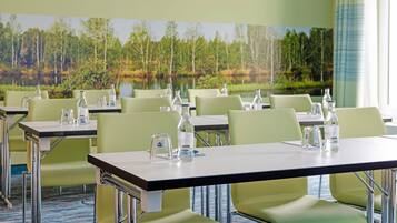 Une salle de conférence équipée de tables, de chaises et de bouteilles d’eau.