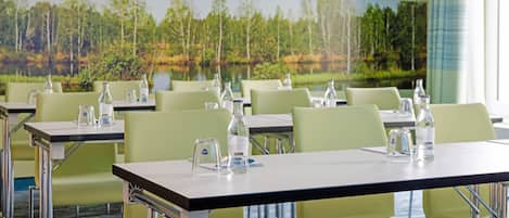 Une salle de conférence équipée de tables, de chaises et de bouteilles d’eau.