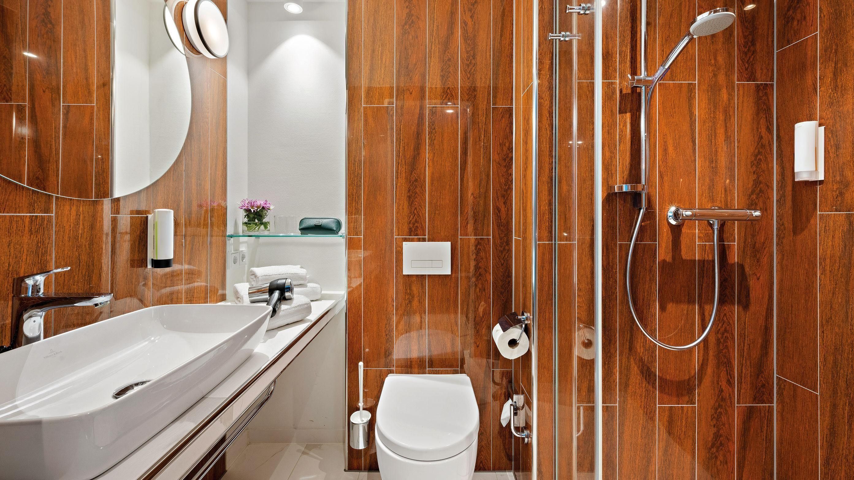 Een moderne badkamer met een groot wit wastafelmeubel, toilet en een inloopdouche met glazen deur.