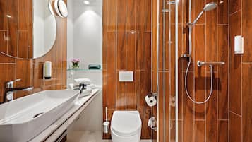 Een moderne badkamer met een groot wit wastafelmeubel, toilet en een inloopdouche met glazen deur.