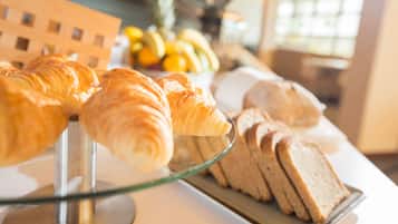 A display of pastries and bread on a glass stand in a bakery.