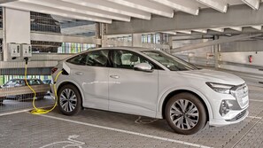A white SUV parked in a covered parking area with a charging station. - Hey Lou Hotel Frankfurt Airport (Kelsterbach)
