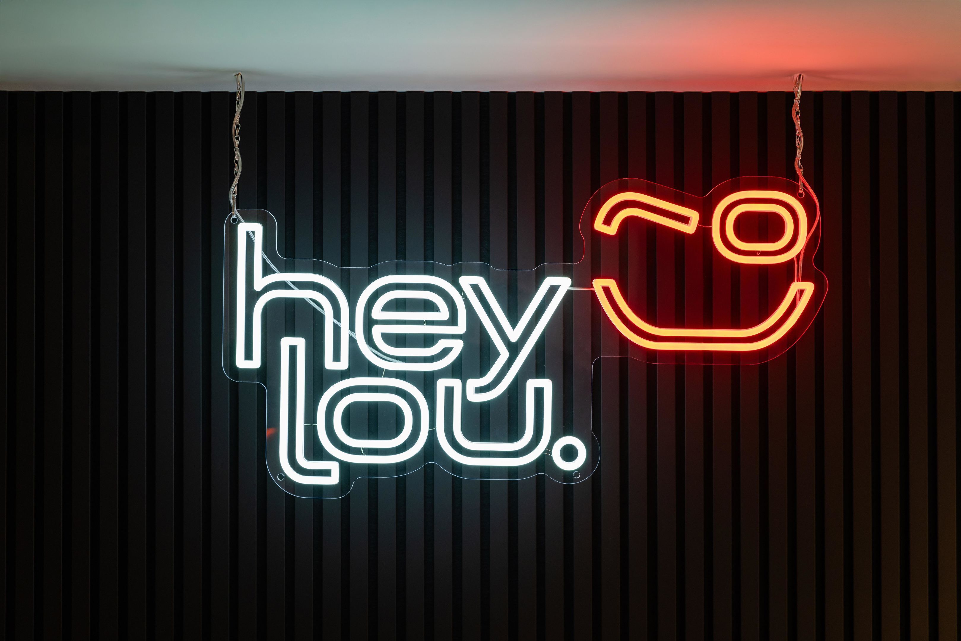 A neon sign with the text 'hey Lou.'
