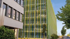 A modern building with a multi-story structure, large windows, and a facade with vertical green and yellow elements. - Hey Lou Hotel Frankfurt Airport (Kelsterbach)