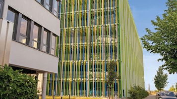 A modern building with a multi-story structure, large windows, and a facade with vertical green and yellow elements.