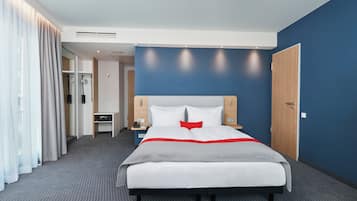 Una habitación de hotel con cama, mesitas de noche, escritorio y armario.