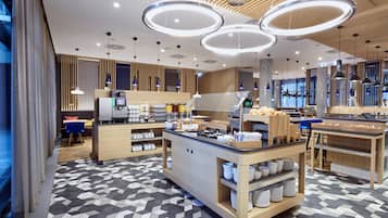 A modern hotel lobby with a central reception desk, seating area, and a patterned floor.