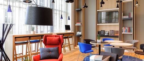 Una biblioteca moderna con diverse zone relax, un'ampia libreria e un televisore a schermo piatto.