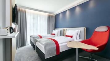 Habitación de hotel con dos camas, un escritorio, un televisor y una silla roja.