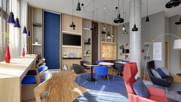 A modern lounge area with wooden tables, blue and red chairs, and a large blue carpet.