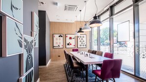 Un'elegante zona pranzo con un tavolo lungo, sedie, lampade a sospensione e quadri appesi alle pareti.