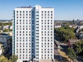 Un hotel moderno de gran altura, con varios pisos y un logotipo destacado en la parte superior.