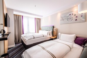 A hotel room with two beds, a TV, a clock, and a window with curtains. - Premier Inn Köln City Süd (Cologne)