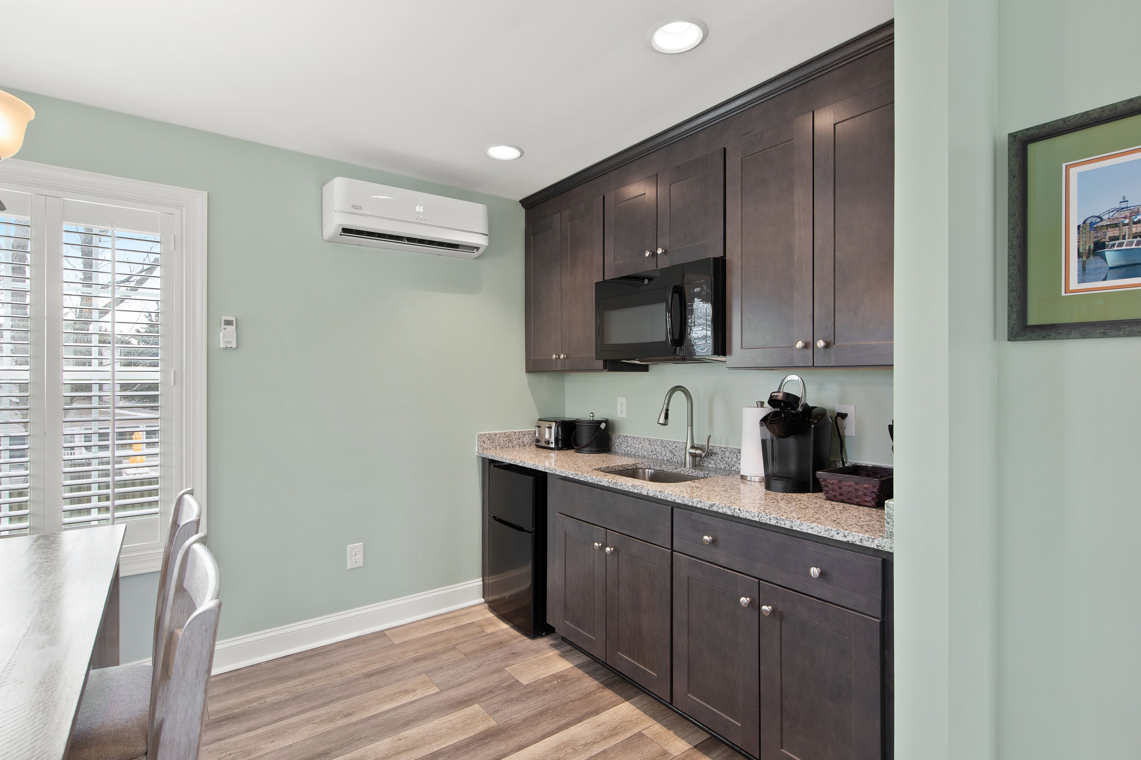 A kitchen with dark cabinets, a microwave, and a sink.