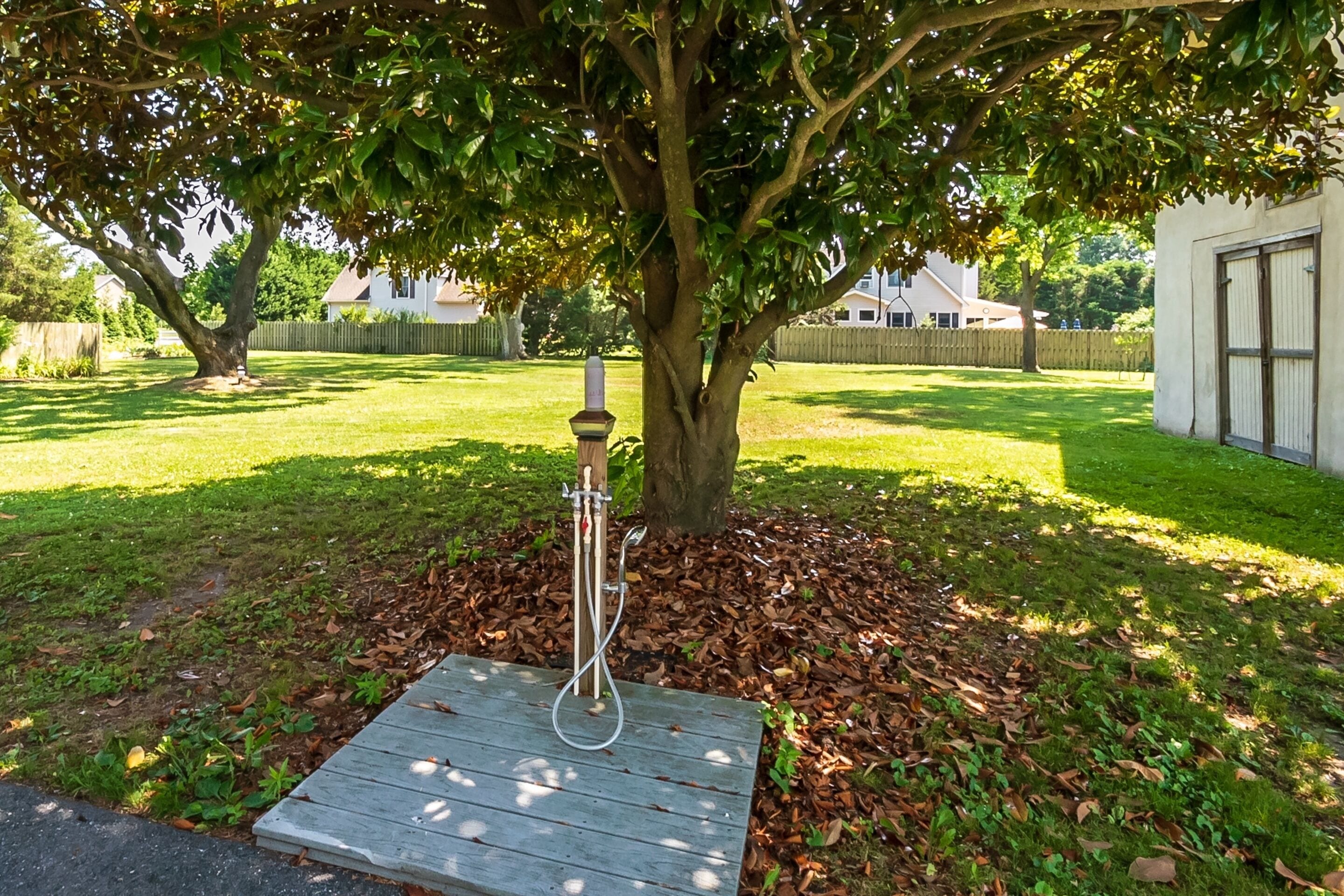 Een houten terras met een metalen constructie onder een boom.