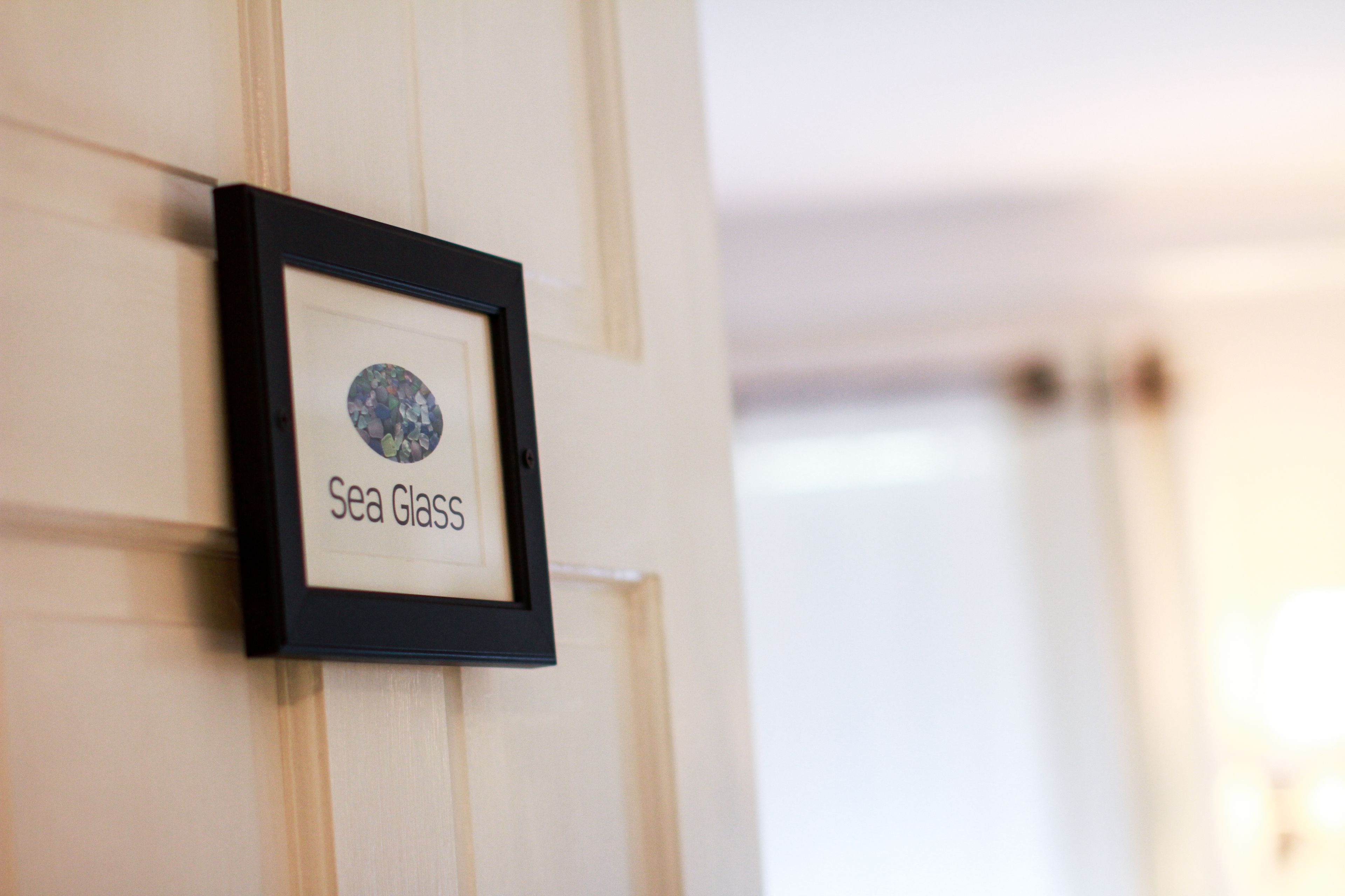A framed picture with the text "Sea Glass" on a wall.