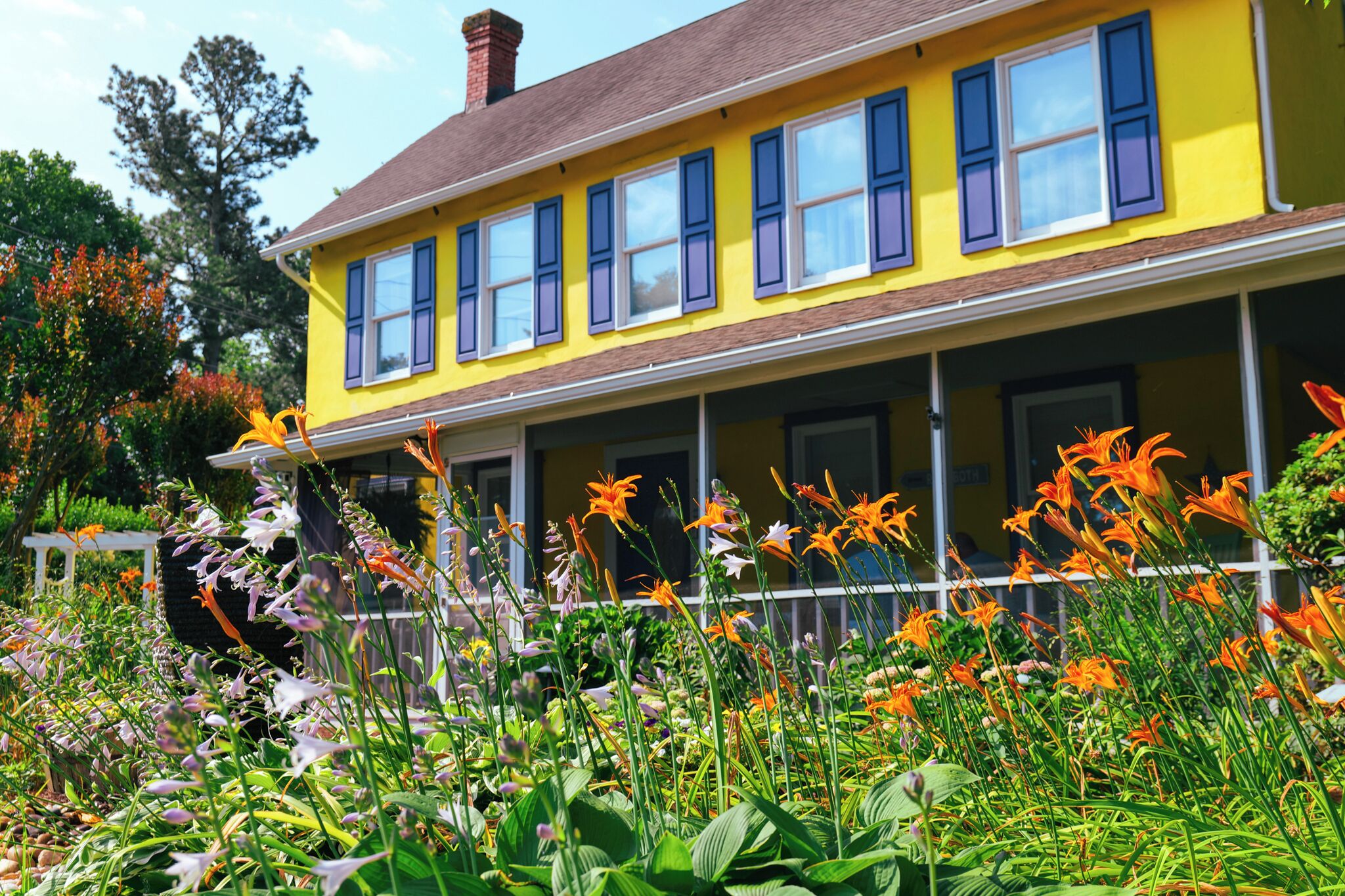 A yellow house with a porch and multiple windows.
